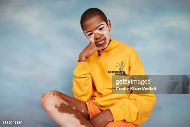 boy in yellow sweatshirt sitting with hand on chin - african kids stylish stock pictures, royalty-free photos & images