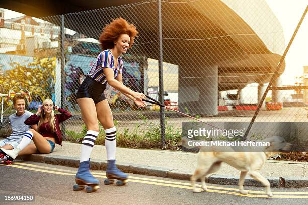 young woman roller skating with dog - rolschaatsen schaats stockfoto's en -beelden