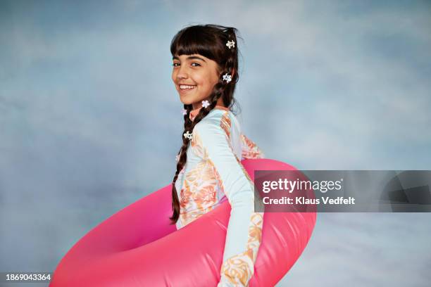 smiling girl carrying pink inflatable ring - tween girls swimwear stock pictures, royalty-free photos & images