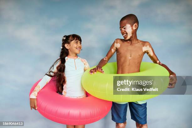 happy friends standing inside of inflatable rings - tween girls swimwear stock pictures, royalty-free photos & images