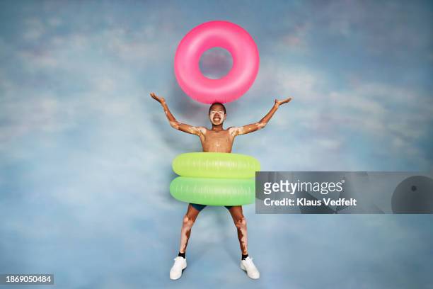 happy boy with vitiligo balancing pink inflatable ring - recreational equipment stock pictures, royalty-free photos & images