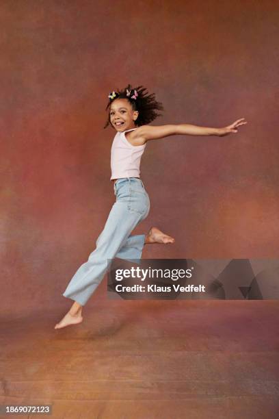 full length of girl jumping mid-air - jeans barefoot girl stock pictures, royalty-free photos & images