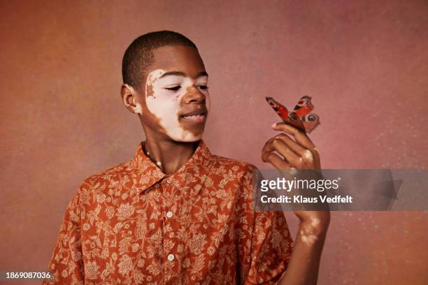 boy with vitiligo admiring butterfly on finger - budding tween stock pictures, royalty-free photos & images