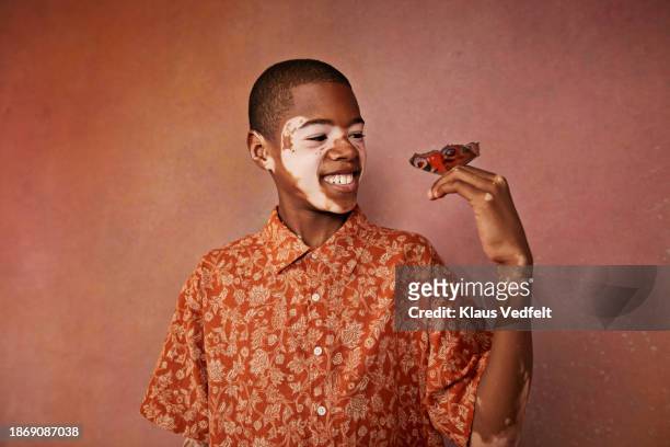 smiling boy with vitiligo looking at butterfly on finger - budding tween stock pictures, royalty-free photos & images