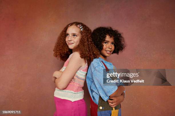 smiling boy and girl standing back to back with arms crossed - budding tween stock pictures, royalty-free photos & images