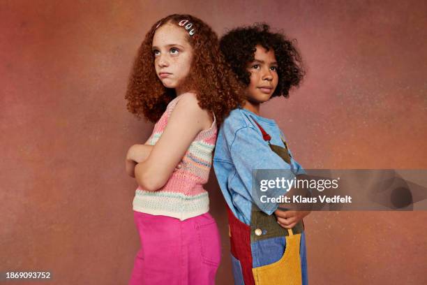 multiracial boy and girl standing back to back with arms crossed - budding tween stock pictures, royalty-free photos & images