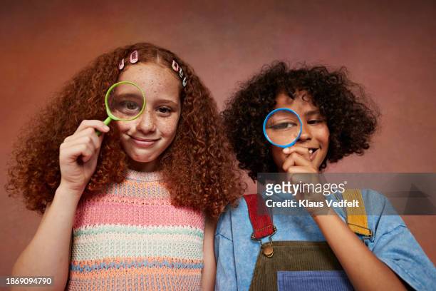 smiling boy and girl looking through magnifying glasses - budding tween stock pictures, royalty-free photos & images