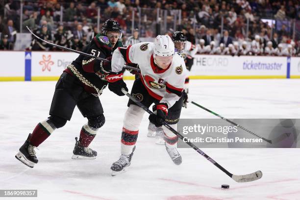 Brady Tkachuk of the Ottawa Senators skates with the puck ahead of Troy Stecher of the Arizona Coyotes during the third period of the NHL game at...