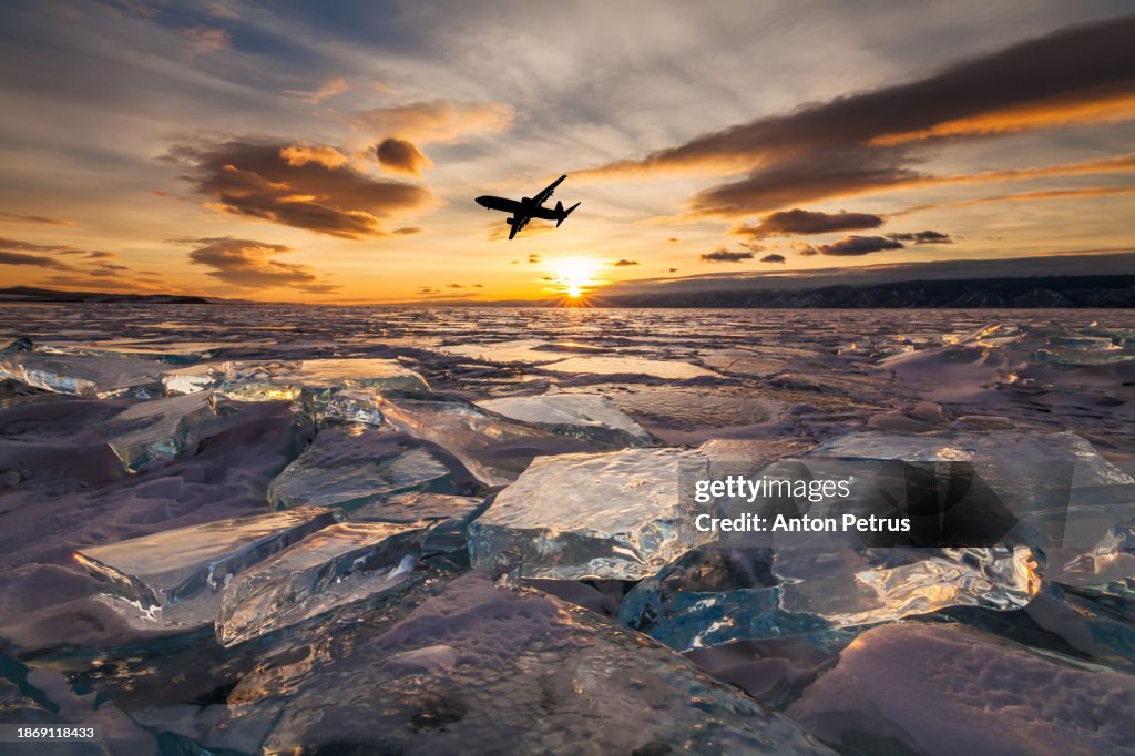 Airplane at sunset under a winter frozen lake