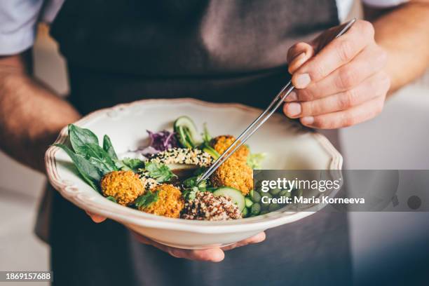 noodles with vegetables and falafel in a white bowl in the hands of the chef. - vegan bildbanksfoton och bilder