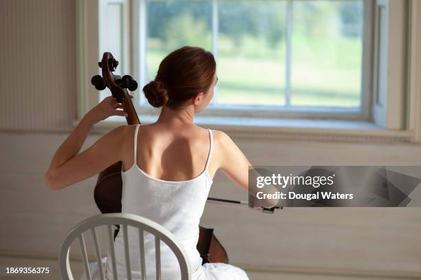 cello player by window - fabolous musician stockfoto's en -beelden