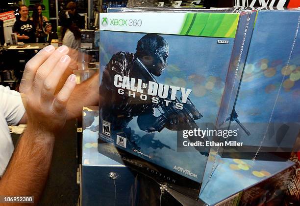 Store manager Brandon Khan grabs a hardened edition copy of "Call of Duty: Ghosts" for the Xbox 360 for a customer during a launch event for the...
