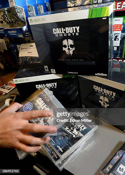 Store manager Brandon Khan stacks copies of "Call of Duty: Ghosts" during a launch event for the highly anticipated video game at a GameStop Corp....