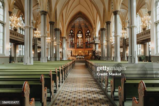 empty walkway amidst benches at church - protestantismus stock-fotos und bilder