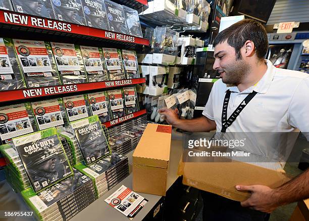 Store manager Brandon Khan stacks copies of "Call of Duty: Ghosts" during a launch event for the highly anticipated video game at a GameStop Corp....