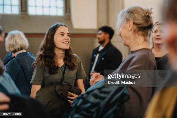 smiling teenage daughter talking with mother after mass at protestant church - middelgrote groep mensen stockfoto's en -beelden
