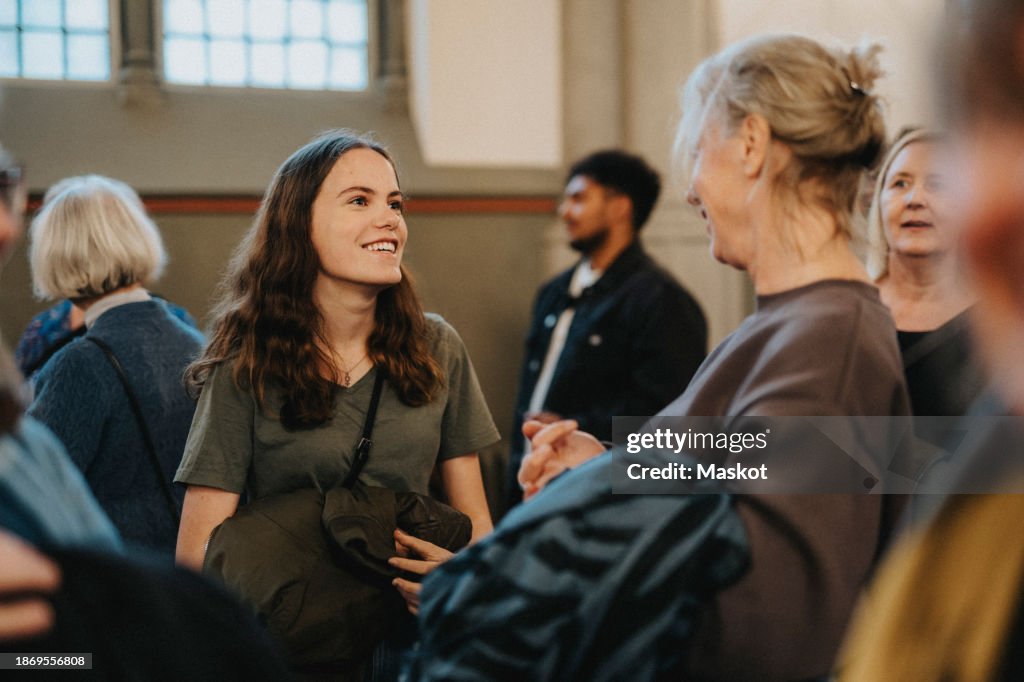 Smiling teenage daughter talking with mother after mass at protestant church