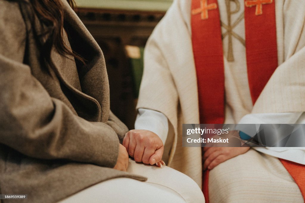 Midsection of female priest consoling woman while sitting at protestant church