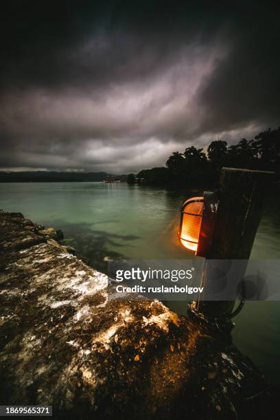 black clouds over an illuminated concrete pier at sunrise, livingston, izabal department, guatemala - livingston guatemala stock pictures, royalty-free photos & images