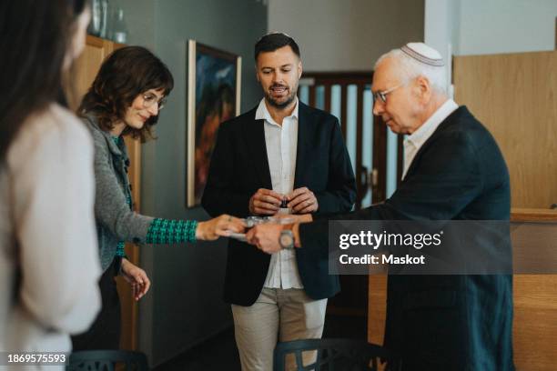 senior man serving wine to woman during jewish congregation at synagogue - jewish tradition stock pictures, royalty-free photos & images