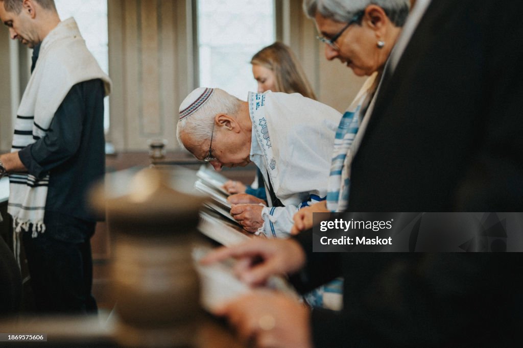 Side view of senior man reciting Amidah during Jewish congregation at synagogue