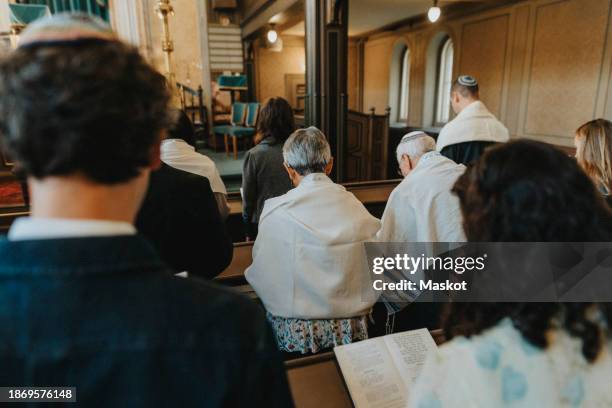 rear view group of people reciting amidah while praying during jewish congregation at synagogue - reading synagogue stock pictures, royalty-free photos & images