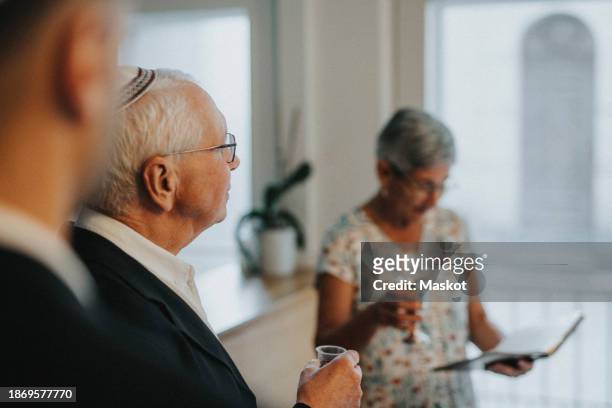 senior man holding drink glass during jewish congregation at synagogue - ユダヤ教の安息日 ストックフォトと画像