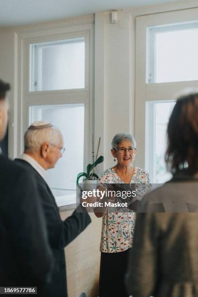 elderly woman toasting drinks during jewish congregation at synagogue - kiddush cup stock-fotos und bilder