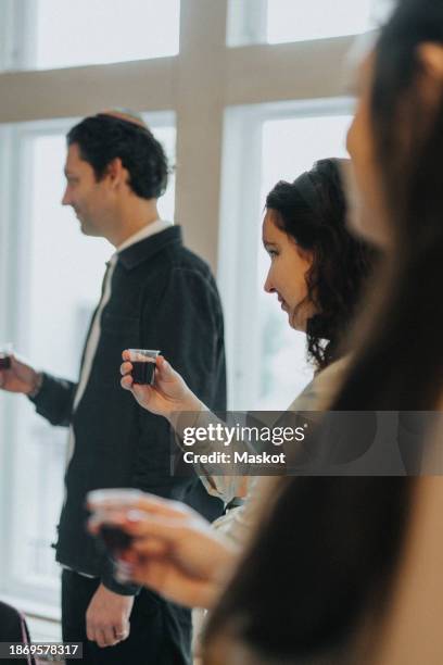 jewish woman toasting wine during congregation at synagogue - kiddush cup stockfoto's en -beelden