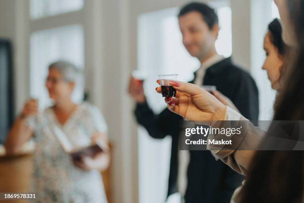 hand of woman toasting wine during jewish congregation at synagogue - kiddush cup stockfoto's en -beelden