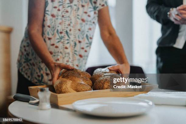 midsection of senior woman holding challah bread in tray during jewish congregation at synagogue - kiddush cup stock-fotos und bilder