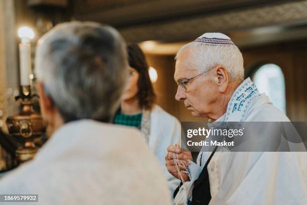 senior man covered in tallit during jewish congregation at synagogue - jewish prayer shawl stock pictures, royalty-free photos & images