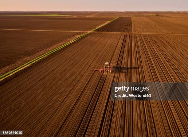 serbia,vojvodinaprovince, aerial view of tractor sowing seeds in plowed corn field - plowed field stock pictures, royalty-free photos & images
