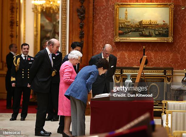 The President of the Republic of Korea Park Geun-Hye , Prince Philip, Duke of Edinburgh and Queen Elizabeth II look at a fan gifted to Queen...
