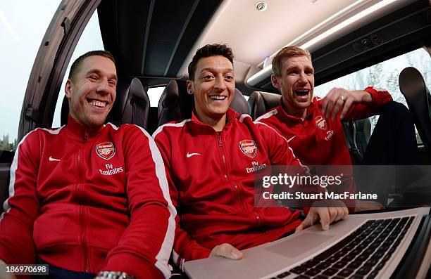 Lukas Podolski, Mesut Oezil and Per Mertesacker of Arsenal travel to the Emirates Aviation Experience on October 31, 2013 in Greenwich, England.