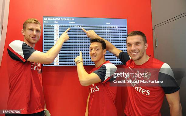 Per Mertesacker, Mesut Oezil and Lukas Podolski of Arsenal at the Emirates Aviation Experience on October 31, 2013 in Greenwich, England.