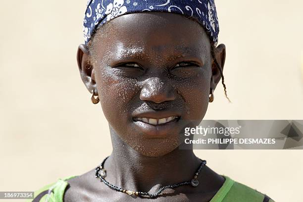 Girl with drops of perspiration on her face looks on as French troops patrol during the Hydra Operation on November 1 in Temera between Timbuktu and...