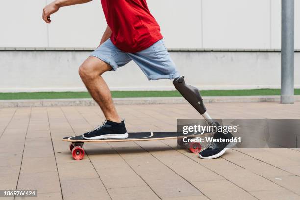 man with prosthetic leg riding skateboard at footpath - prosthetic equipment stock pictures, royalty-free photos & images