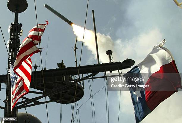 Tomahawk cruise missile flies past an American and a Texas state flag after being launched from the AEGIS guided missile cruiser from the USS San...