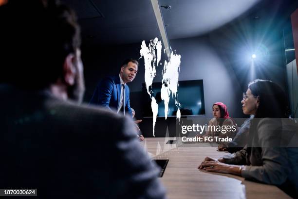 hombre de negocios usando holograma durante una reunión en la oficina - holographic-map fotografías e imágenes de stock