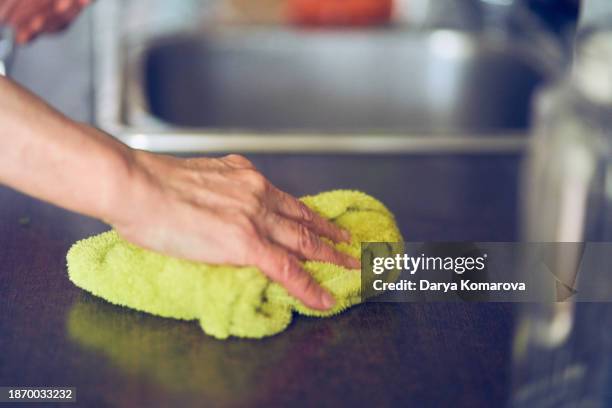 a woman wipes the table with a towel. a household routine for an elderly housewife. - spültuch stock-fotos und bilder