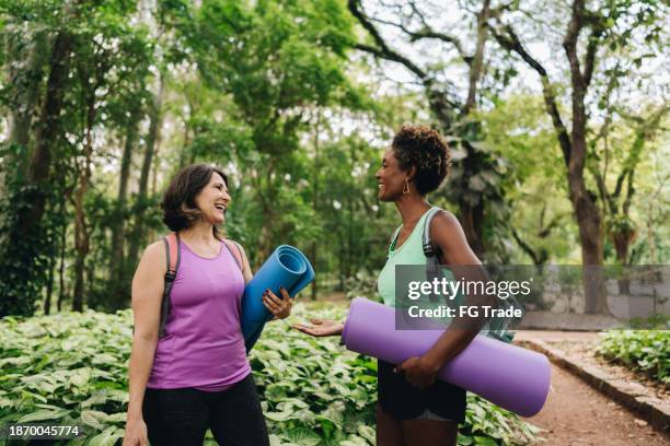 friends holding exercise mats talking on the public park - verloren generatie stockfoto's en -beelden