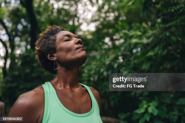 donna matura che si rilassa e respira nel parco pubblico - prendersi cura del corpo foto e immagini stock