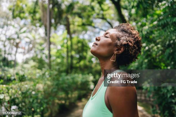 mujer madura relajándose y respirando en el parque público - personas-de-color fotografías e imágenes de stock