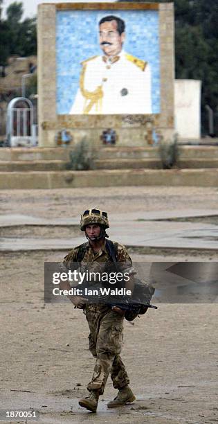 British soldier from 4-2 Commando Brigade patrols a road in front of a mural of Iraqi President Saddam Hussein near the old port March 25, 2003 in...