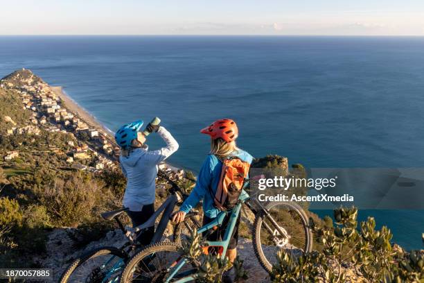 mère et fille cyclistes sur le bord de la montagne - liguria stock photos et images de collection