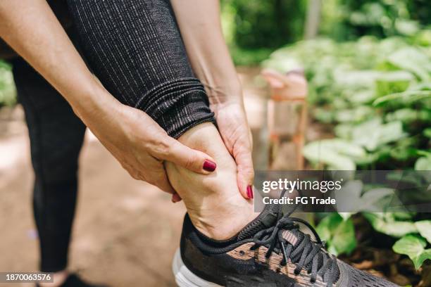close-up of woman with pain on ankle on the public park - sprain stock pictures, royalty-free photos & images