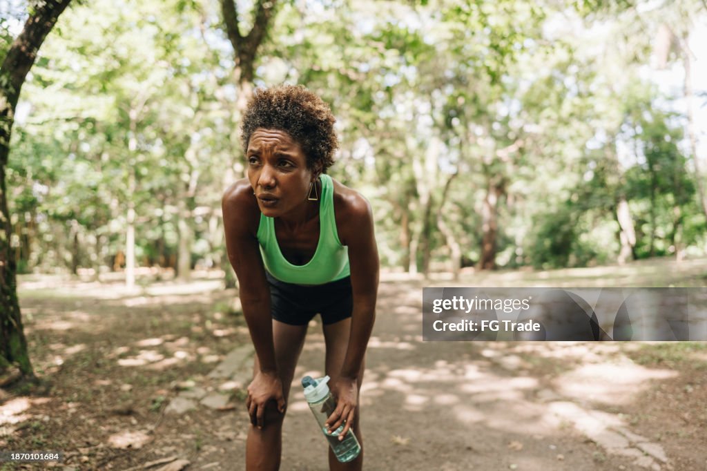 Tired mature woman out of breath after running on the public park