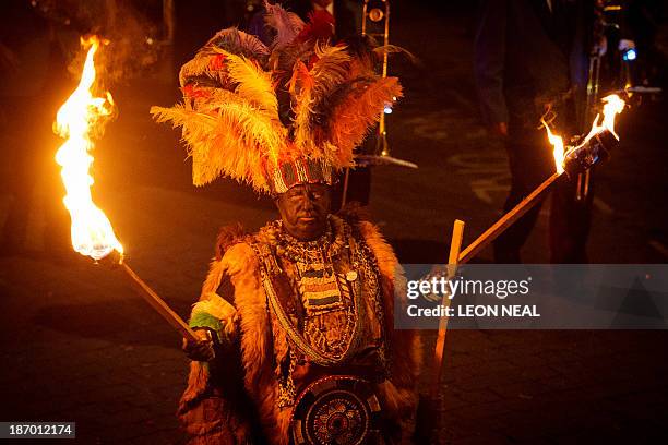 Participant in costume holds aloft torches during the Bonfire Night celebrations on November 5, 2013 in Lewes, Sussex in England.Bonfire Night is...