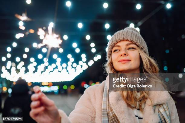 happy new year on night streets. sparklers in woman hand for celebration - bengalischer feuer stock-fotos und bilder